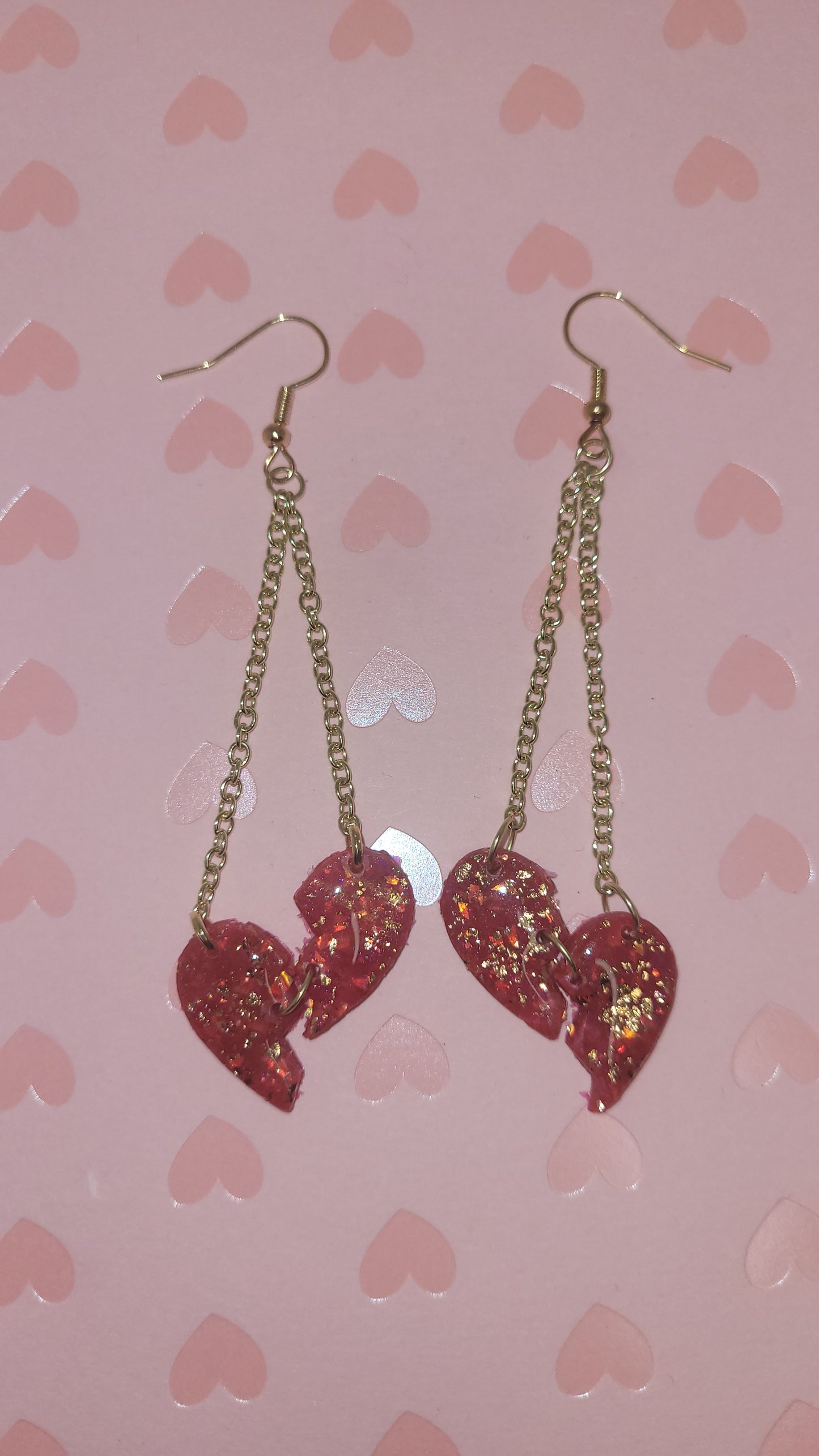 heartbreak dangles laid on a pink heart background (with flash)