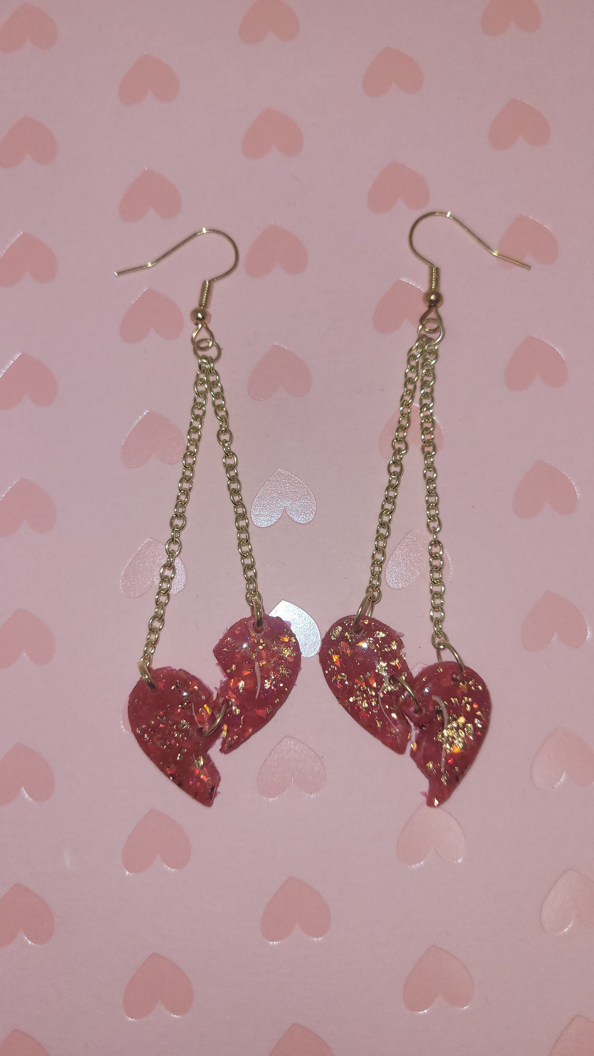 heartbreak dangles laid on a pink heart background (with flash)